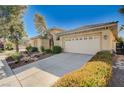 Beige home with wide driveway leading to a two-car garage and desert landscaping, showcasing a serene ambiance at 3663 Coventry Gardens Dr, Las Vegas, NV 89135