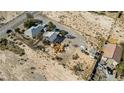 A high-angle view reveals two houses with sheds, surrounded by a dirt lot in a rural setting at 4838 N Tioga Way, Las Vegas, NV 89149