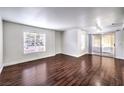 Open-concept living area with hardwood floors, a ceiling fan, large window, and sliding door to the outside at 6800 E Lake Mead Blvd # 1047, Las Vegas, NV 89156
