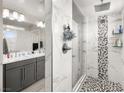 Modern bathroom featuring a glass-enclosed shower with tile surround, pebble floor, and double sink vanity at 70 Pikiariki Ct, Las Vegas, NV 89183