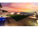 Expansive backyard featuring an artificial lawn, gravel accents, and serene sunset views at 10216 Chrysolite Pl, Las Vegas, NV 89143