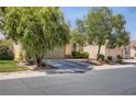 Beautiful home exterior featuring a two-car garage, lush landscaping with mature trees, and a well-maintained driveway at 1375 Gran Vista Ave, Henderson, NV 89012