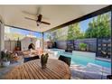 A covered outdoor living space, complete with a pool, spa, fireplace, and ceiling fan at 2132 Ponticino St, Henderson, NV 89044