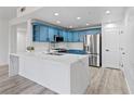 Modern kitchen featuring blue cabinets, stainless steel appliances, a white marble countertop island, and light gray wood flooring at 2325 Windmill Pkwy # 1711, Henderson, NV 89074