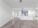 Open-concept living room with gray wood flooring and a view of the kitchen with blue cabinets and a white marble countertop island at 2325 Windmill Pkwy # 1711, Henderson, NV 89074