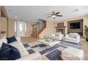 Bright living room featuring a fireplace, ceiling fan, staircase, and comfortable seating at 8216 Swallow Falls St, North Las Vegas, NV 89085