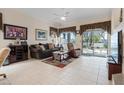 A cozy living room with tile flooring, a comfortable sofa, and a sliding glass door to the backyard at 10563 Sunblower Ave, Las Vegas, NV 89135