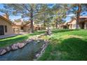 Beautiful landscaping in backyard with water feature, grass and mature trees at 7913 Sailboat Ln, Las Vegas, NV 89145