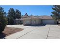 Charming single-story home featuring an attached garage, mature evergreens, and a large concrete driveway at 821 W Amarillo Ave, Pahrump, NV 89048