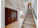 The home's foyer shows tile flooring, wooden doors, staircase and a view into the kitchen at 9010 W Lone Mountain Rd, Las Vegas, NV 89129