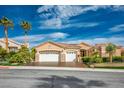 Attractive single-story home featuring a three-car garage, desert landscaping, and a well-maintained lawn at 10524 Longwood Dr, Las Vegas, NV 89134