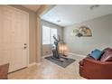 Neutral-toned room with tile flooring, an exercise bike, a leather sofa, and a large window at 10960 Prairie Grove Rd, Las Vegas, NV 89179