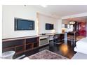 Bright living area featuring dark wood flooring, built-in shelving with a TV, desk, and partially open kitchen at 4381 W Flamingo Rd # 2605, Las Vegas, NV 89103