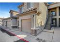 Beige two-story building with a tile roof, garages, stairway, and sidewalks at 4685 Apulia Dr # 202, North Las Vegas, NV 89084