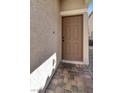 A welcoming front entrance with a six-panel door, textured stucco, and brick walkway at 5614 Bishop Flowers St, Las Vegas, NV 89130