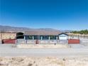 Charming single-story home with a red gate, desert landscaping, and mountain views at 9090 Josepine St, Pahrump, NV 89048