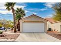 Attached garage with a white door and a concrete driveway in front of a charming home with palm trees at 1645 Indian Cove Ln, Las Vegas, NV 89128