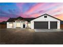 Single-story home with a two-car garage against a colorful sunset sky at 1660 W Princeton Cir, Pahrump, NV 89060