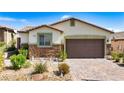 Charming single-story home featuring a desert landscape, stone accents, and a two-car garage at 2612 Tullamore Creek Ln, Laughlin, NV 89029