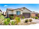 Charming single-story home featuring a desert landscape, stone accents, and a two-car garage at 2612 Tullamore Creek Ln, Laughlin, NV 89029