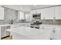 Modern kitchen with white cabinets, stainless steel appliances, gray backsplash, and a center island with a marble countertop at 3212 Hickey Ave, North Las Vegas, NV 89030