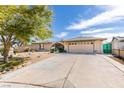 View of the house with a large driveway, desert landscaping, and an attached two-car garage at 4476 Oakhill Cir, Las Vegas, NV 89121