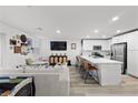 Open-concept living space with a modern kitchen, comfortable seating, and natural light from large windows at 6144 Rathbone St, Las Vegas, NV 89166