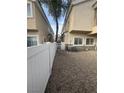 Fenced backyard featuring neutral gravel landscaping, and view of the home's exterior with windows and an air conditioning unit at 6461 Za Zu Pitts Ave # 102, Las Vegas, NV 89122