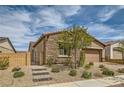 Single-story home boasts stone accents, a two-car garage, brick driveway, and an enclosed front yard with stone steps at 728 Omaggio Pl, Henderson, NV 89011
