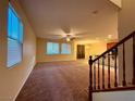 Spacious living room featuring a ceiling fan, large windows, and neutral carpeting at 10145 White Mulberry Dr, Las Vegas, NV 89148
