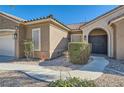 Close-up of the front entrance featuring a tiled roof, arched doorway, and well-maintained desert landscaping at 3017 Walnut Park Ct, Henderson, NV 89052