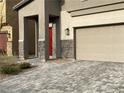 Close up of a home's exterior showing stone accents, a red door, and a well-maintained driveway at 4243 Sago Lily St, Las Vegas, NV 89129