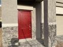 A closer view of a red front door with stone pillars and a stone facade accenting the home's entrance at 4243 Sago Lily St, Las Vegas, NV 89129
