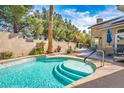 Refreshing pool with steps, surrounded by lush greenery and a serene patio area with outdoor seating at 4574 Sheri Lyn Ct, Las Vegas, NV 89121