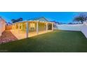 Spacious backyard with covered patio, manicured artificial grass, and decorative string lights at 7341 Girard Dr, Las Vegas, NV 89147
