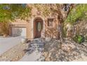 Inviting entryway with an arched front door, decorative planters, and attractive desert landscaping at 11673 Pride Hill St, Las Vegas, NV 89183
