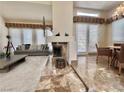 Comfortable living room with stone fireplace and marble floors, complete with a gray sofa and accent furniture at 5010 Longboat Cir, Las Vegas, NV 89113