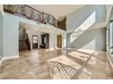 Bright and spacious living room with soaring ceilings, travertine flooring, and a wrought iron staircase at 5337 Polizze Ave, Las Vegas, NV 89141