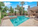 Backyard pool and spa combo featuring stone accents, a covered patio, and mature landscaping at 7715 Villa De La Paz Ave, Las Vegas, NV 89131