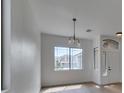 Bright living room features a window with a neighborhood view and modern chandelier at 10452 Niagara Falls Ln, Las Vegas, NV 89144