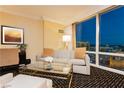 Comfortable sitting area features a sofa, side chair, glass coffee table, and expansive views of the city at 2000 Fashion Show Dr # 5300, Las Vegas, NV 89109