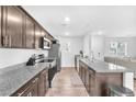 Modern kitchen with stainless steel appliances, granite countertops, and ample cabinet space with seamless flow to living area at 7017 Magenta Moon St, North Las Vegas, NV 89086