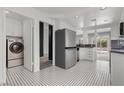 Bright kitchen featuring stainless steel appliances, black and white tile floor, and adjacent laundry area at 1403 Bareback Ct, Henderson, NV 89014