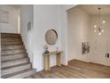 Bright foyer with wood-look floors, stairs, and a round mirror over a console table at 2685 S Tenaya Way, Las Vegas, NV 89117