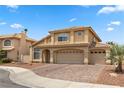 Two-story home with tan stucco exterior, tile roof, brick driveway, and three-car garage at 2716 Timber Crossing Ct, Henderson, NV 89074