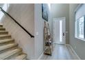 Bright entryway featuring tiled floors, stairs, a modern shelf, and a front door with a large glass panel at 3217 Bertonico Ave, Henderson, NV 89044