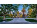 Beautiful home exterior featuring a manicured lawn, mature trees, and an elegant driveway at 1108 Pine Island Ct, Las Vegas, NV 89134