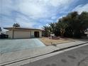 View of the house with a desert landscape, mature trees and a driveway that leads to a two-car garage at 2501 Capistrano Ave, Las Vegas, NV 89121