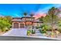 Elegant two-story home featuring a stone archway, tiled roof, two-car garage, and lush landscaping at 5 Via Ravenna Ct, Henderson, NV 89011