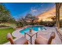 Inviting pool and spa featuring waterfall feature, patio dining set, lounge chairs and sunset views at 5 Via Ravenna Ct, Henderson, NV 89011